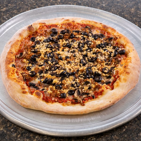 A whole pizza with black olives, crumbled sausage, and mushrooms on a metal tray.
