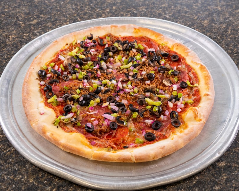A whole pizza with pepperoni, sausage, mushrooms, black olives, green peppers, and red onions.