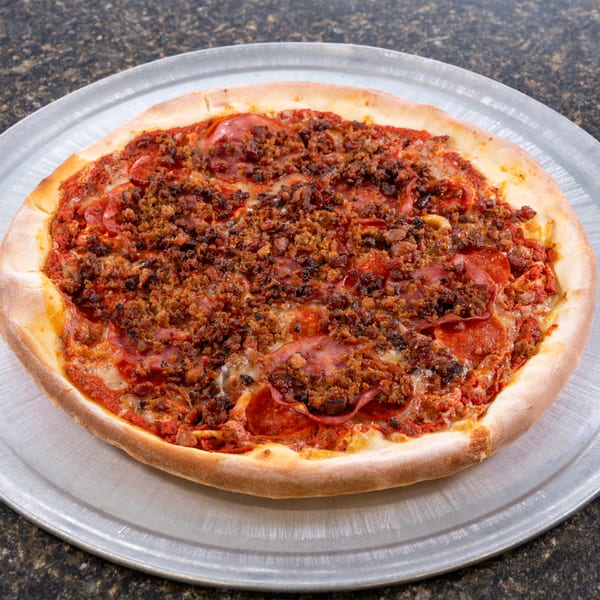 A whole meat lover's pizza with pepperoni and sausage on a metal pizza pan.