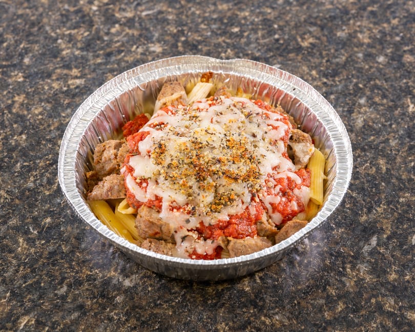 Baked ziti with sausage, marinara, and melted cheese in a foil takeout container.