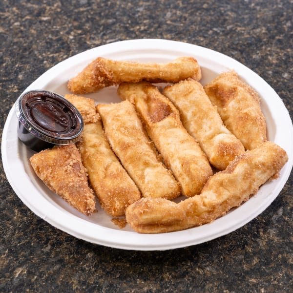 A white plate filled with golden-brown churro sticks and a small cup of chocolate dipping sauce.